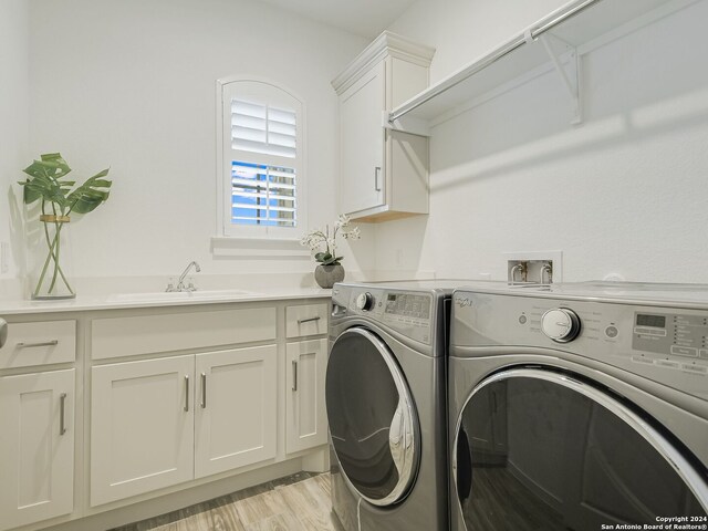 clothes washing area featuring light hardwood / wood-style floors, hookup for a washing machine, sink, washer and clothes dryer, and cabinets