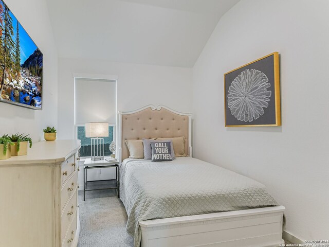 bedroom featuring light colored carpet and vaulted ceiling