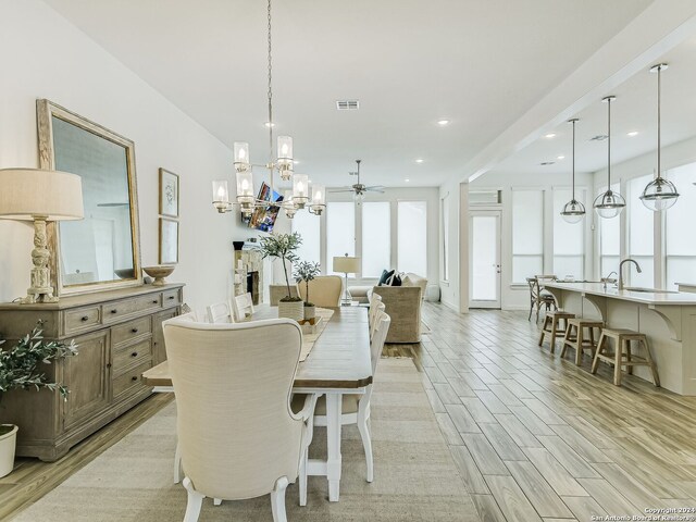 dining space featuring light hardwood / wood-style flooring and ceiling fan with notable chandelier