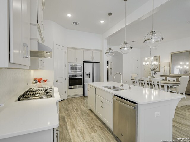 kitchen featuring appliances with stainless steel finishes, sink, white cabinets, and a center island with sink