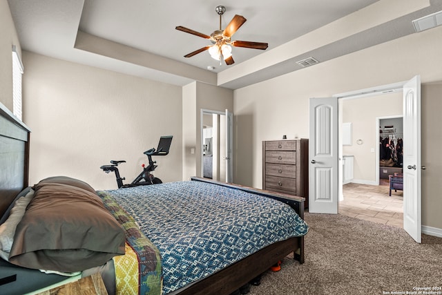 carpeted bedroom featuring ceiling fan and a tray ceiling