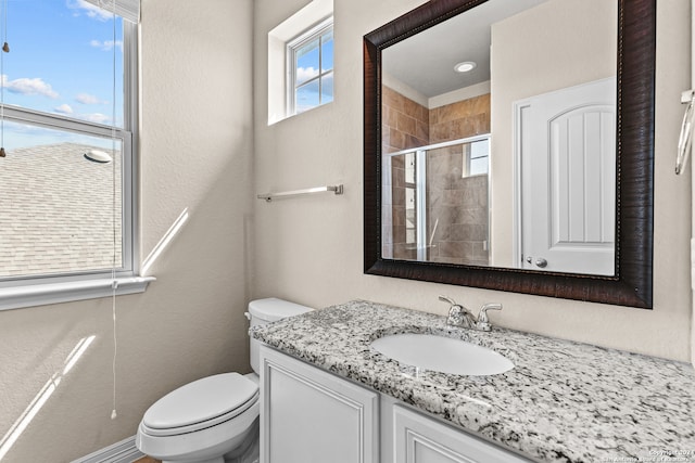 bathroom featuring toilet, vanity, and a shower with door