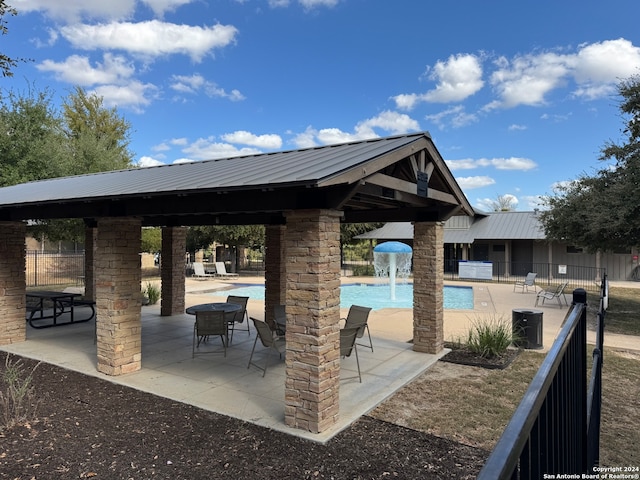 view of patio with a gazebo, a community pool, and pool water feature