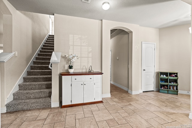 interior space featuring a textured ceiling and white cabinets