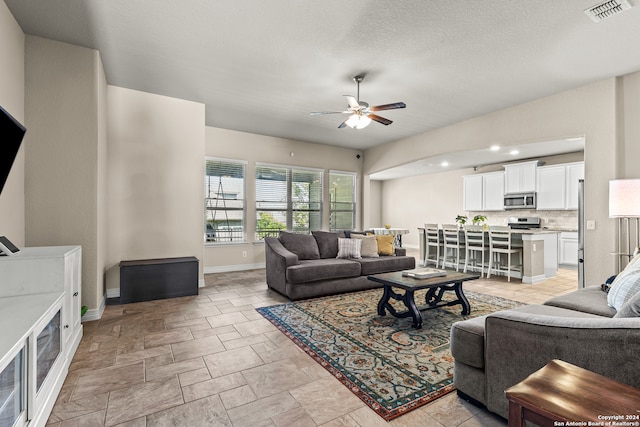 living room with a textured ceiling and ceiling fan