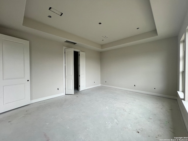 unfurnished bedroom featuring concrete flooring and a tray ceiling