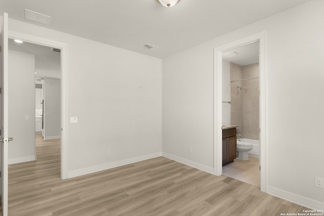 unfurnished bedroom featuring light wood-type flooring and ensuite bath