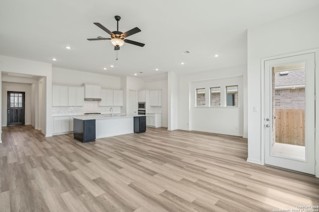 unfurnished living room featuring ceiling fan, light wood-type flooring, sink, and a healthy amount of sunlight