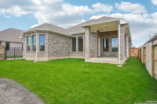 back of house featuring a lawn and a patio area