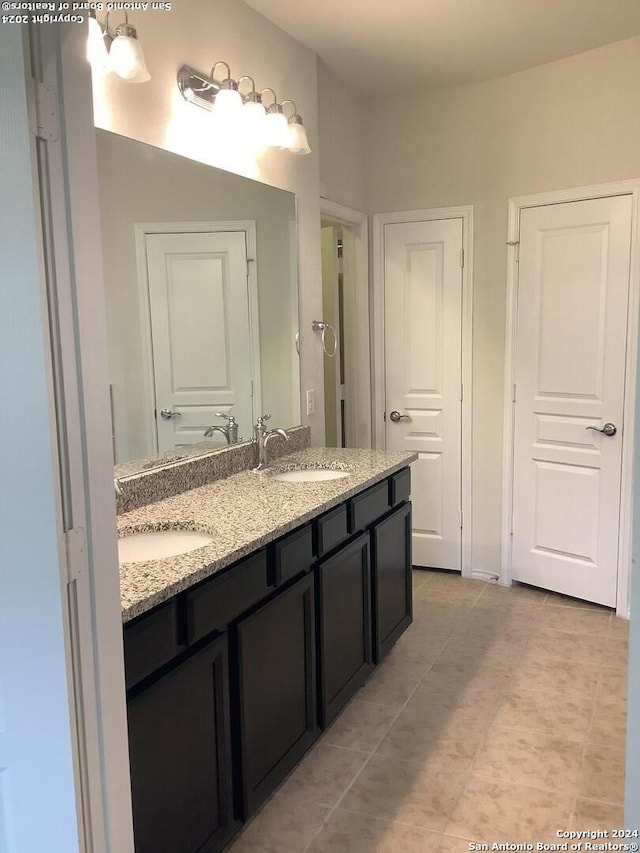 bathroom featuring vanity with extensive cabinet space, dual sinks, and tile floors