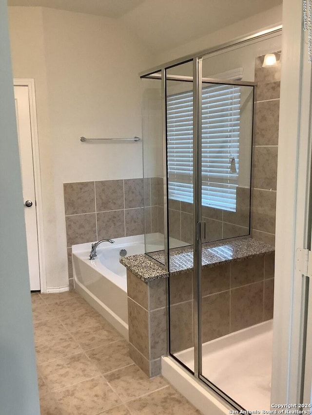 bathroom featuring tile flooring and shower with separate bathtub