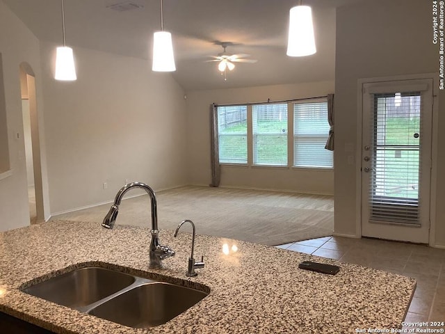 kitchen featuring vaulted ceiling, light stone counters, ceiling fan, light carpet, and sink