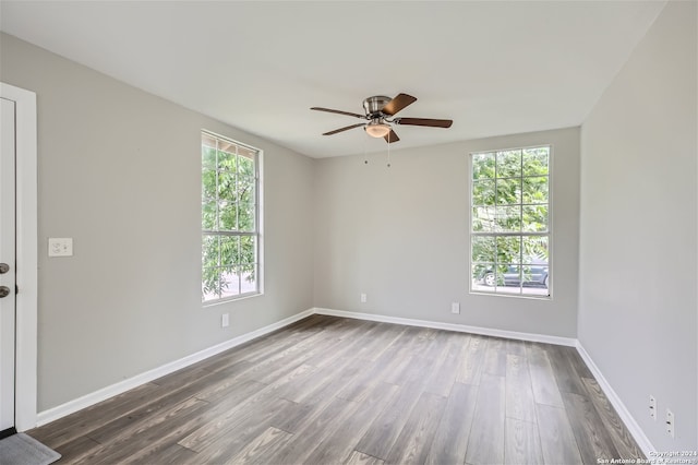 empty room featuring plenty of natural light, ceiling fan, and dark hardwood / wood-style flooring