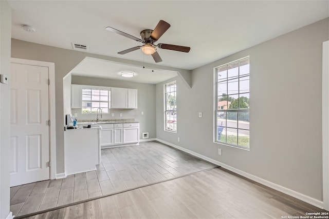 unfurnished living room with light hardwood / wood-style floors, a wealth of natural light, and ceiling fan