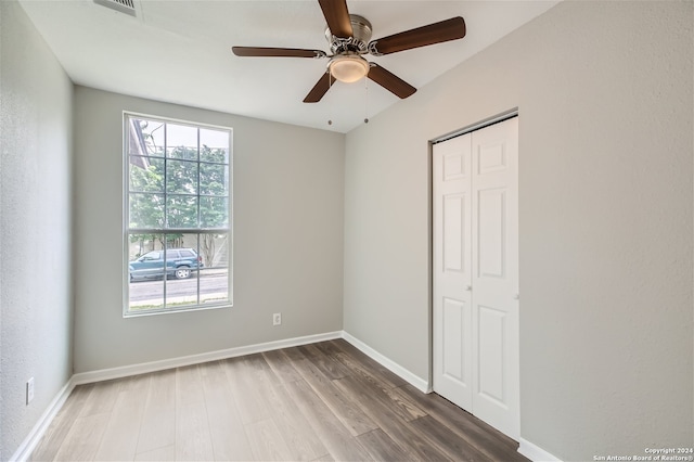 unfurnished room featuring a wealth of natural light, wood-type flooring, and ceiling fan