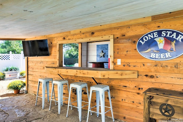 bar with plenty of natural light, wood walls, and wood ceiling