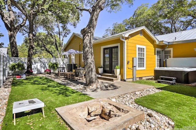 back of house featuring a patio, a hot tub, and a yard