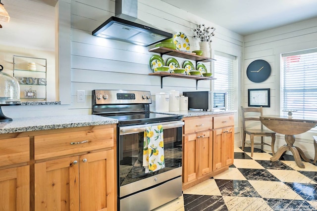 kitchen featuring wall chimney range hood, light tile flooring, stainless steel electric range oven, light stone countertops, and wooden walls