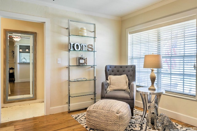 living area with wood-type flooring and ornamental molding