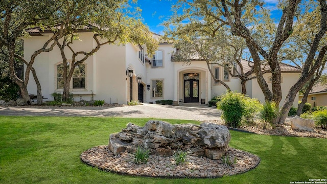 mediterranean / spanish-style house featuring french doors and a front lawn