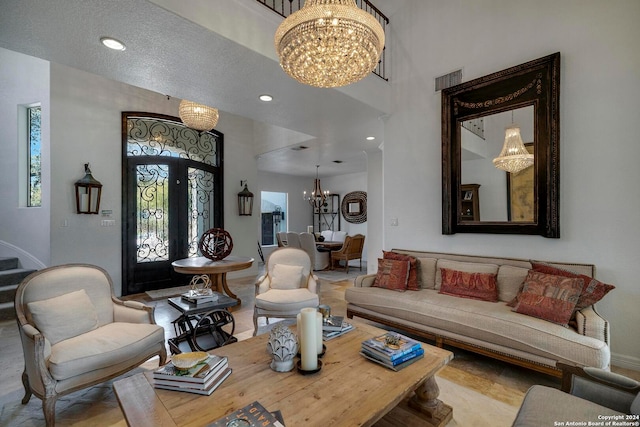 living room featuring french doors, a textured ceiling, and an inviting chandelier