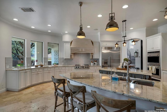 kitchen featuring appliances with stainless steel finishes, sink, hanging light fixtures, custom exhaust hood, and white cabinets