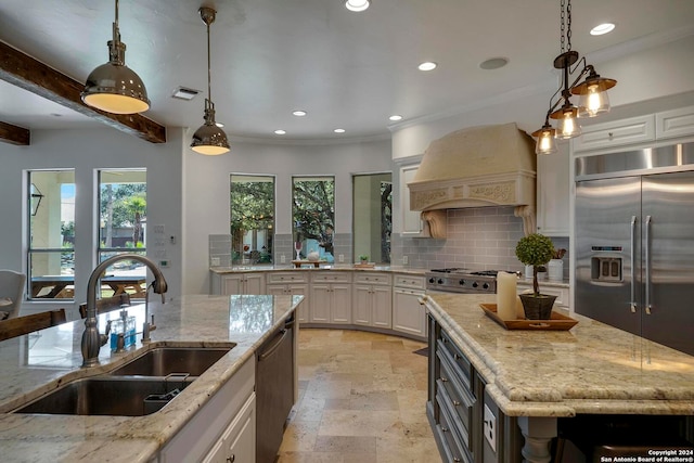 kitchen with white cabinetry, sink, light stone counters, and an island with sink