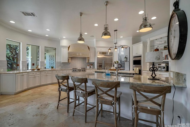 kitchen with white cabinets, pendant lighting, premium range hood, appliances with stainless steel finishes, and tasteful backsplash