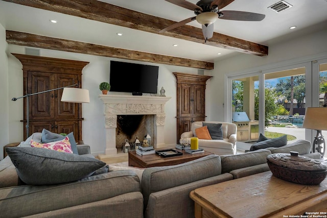 living room featuring beamed ceiling, a fireplace, and ceiling fan