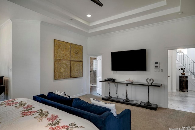 carpeted bedroom with crown molding, ensuite bathroom, and a raised ceiling