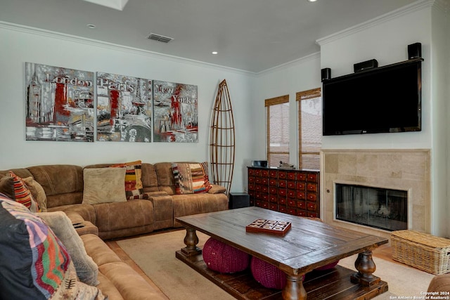 living room with crown molding, a tiled fireplace, and wood-type flooring