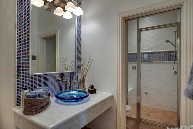 bathroom featuring decorative backsplash, walk in shower, toilet, sink, and tile patterned floors