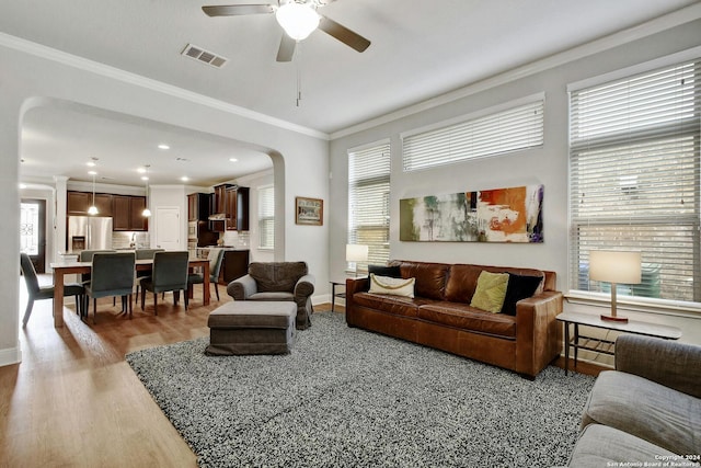 living room with light wood-type flooring, crown molding, and ceiling fan