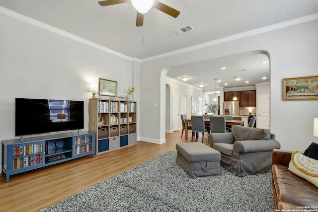 living room with ceiling fan, light hardwood / wood-style flooring, and crown molding