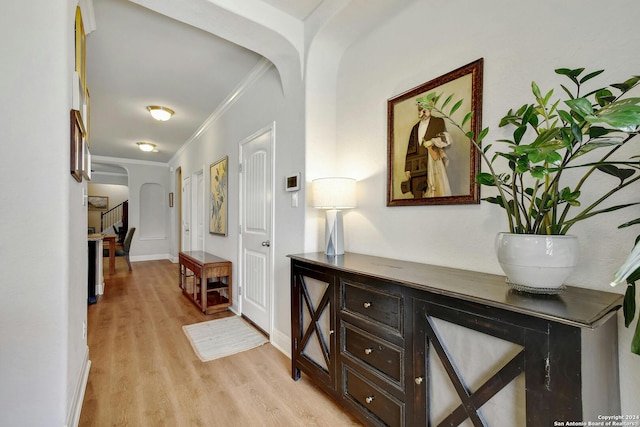 corridor with light wood-type flooring and ornamental molding