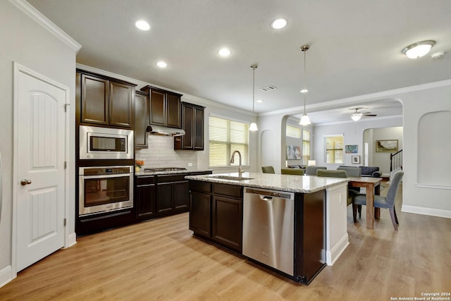 kitchen with backsplash, a kitchen island with sink, appliances with stainless steel finishes, light hardwood / wood-style floors, and sink