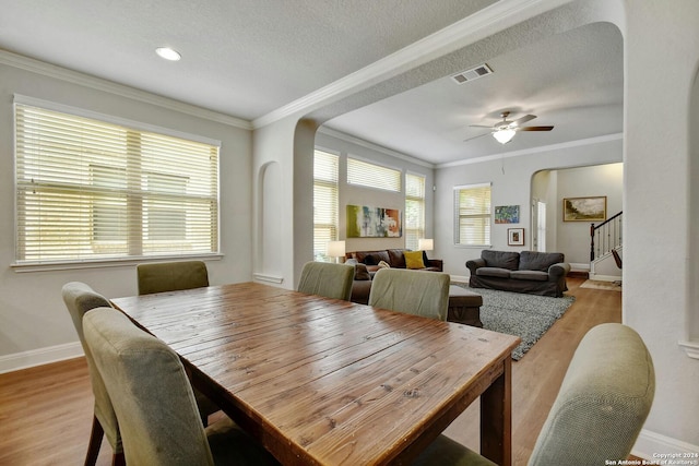 dining area featuring hardwood / wood-style flooring, a textured ceiling, crown molding, and ceiling fan