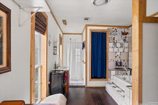 interior space featuring a bath, crown molding, and hardwood / wood-style flooring