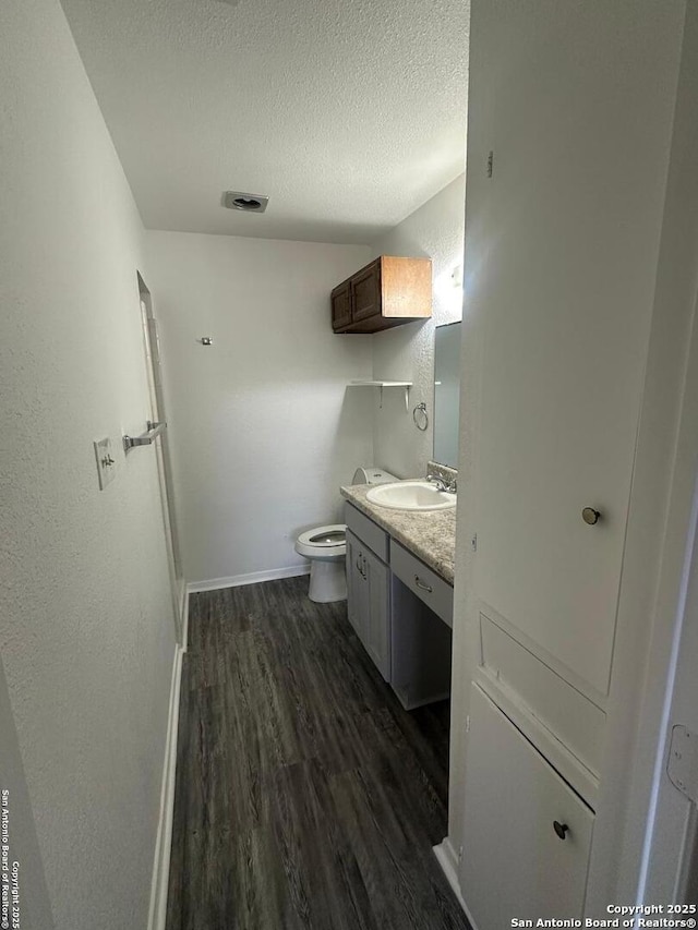 bathroom featuring a textured ceiling, vanity, toilet, and hardwood / wood-style floors