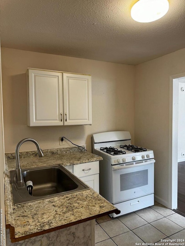 kitchen featuring sink, white cabinetry, white range with gas cooktop, and light tile floors