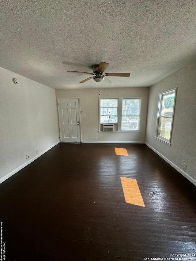 unfurnished room with a textured ceiling, dark wood-type flooring, and ceiling fan