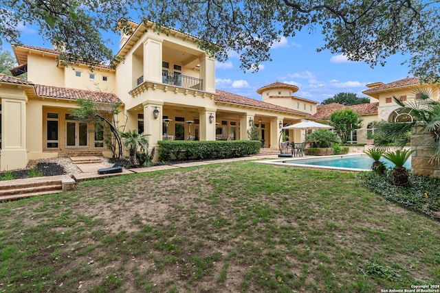 rear view of house featuring a lawn, a patio area, and a balcony