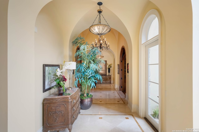 corridor featuring a healthy amount of sunlight and an inviting chandelier