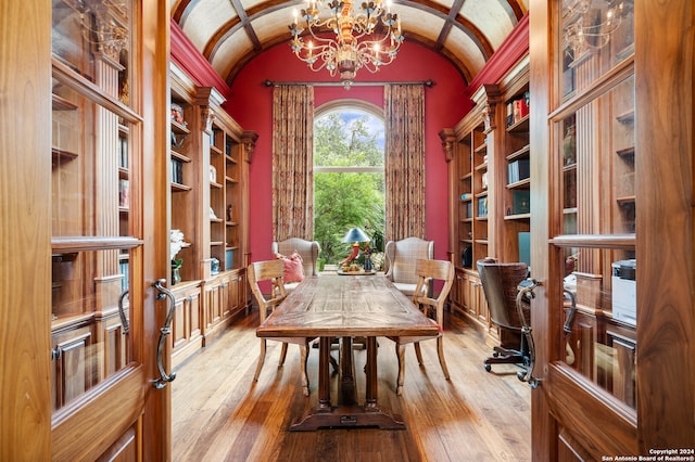 office with hardwood / wood-style flooring, lofted ceiling, brick ceiling, and an inviting chandelier