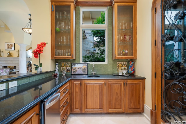 bar featuring tasteful backsplash, dark stone countertops, sink, and pendant lighting