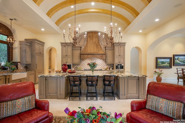 kitchen with a large island with sink, sink, decorative light fixtures, and vaulted ceiling