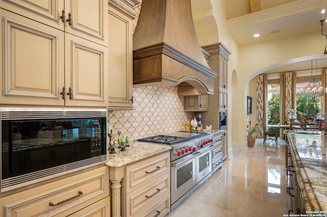 kitchen featuring pendant lighting, custom exhaust hood, double oven range, light stone countertops, and black microwave