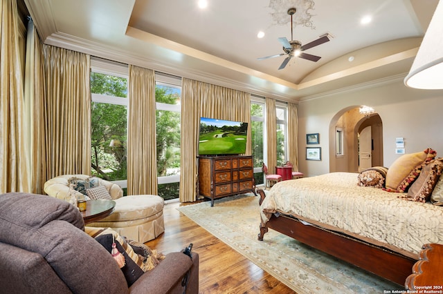 bedroom featuring light wood-type flooring, ornamental molding, a tray ceiling, vaulted ceiling, and ceiling fan