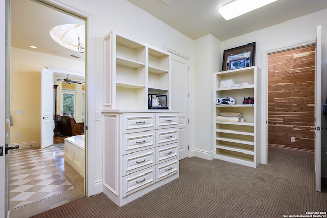 walk in closet with dark colored carpet and ceiling fan