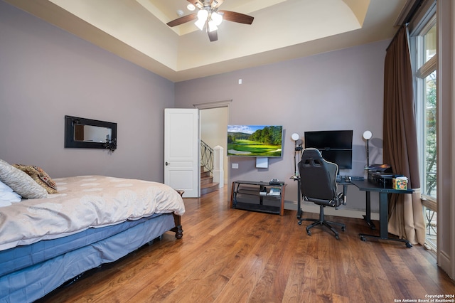 bedroom featuring hardwood / wood-style floors, ceiling fan, and a raised ceiling